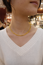 Gold plated chain necklace worn by a person 
