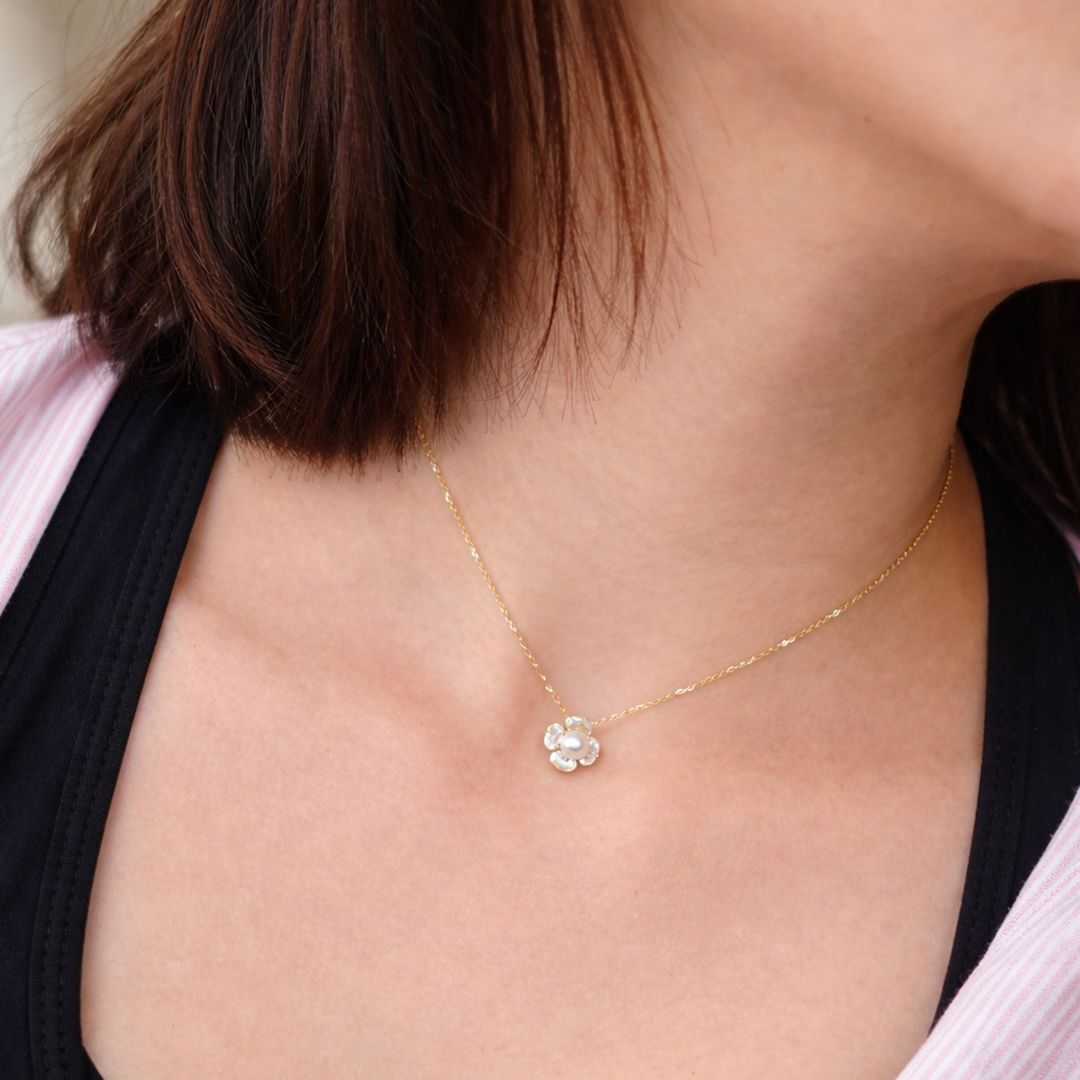 person wearing a delicate sterling silver gold plated necklace with a flower pendant.