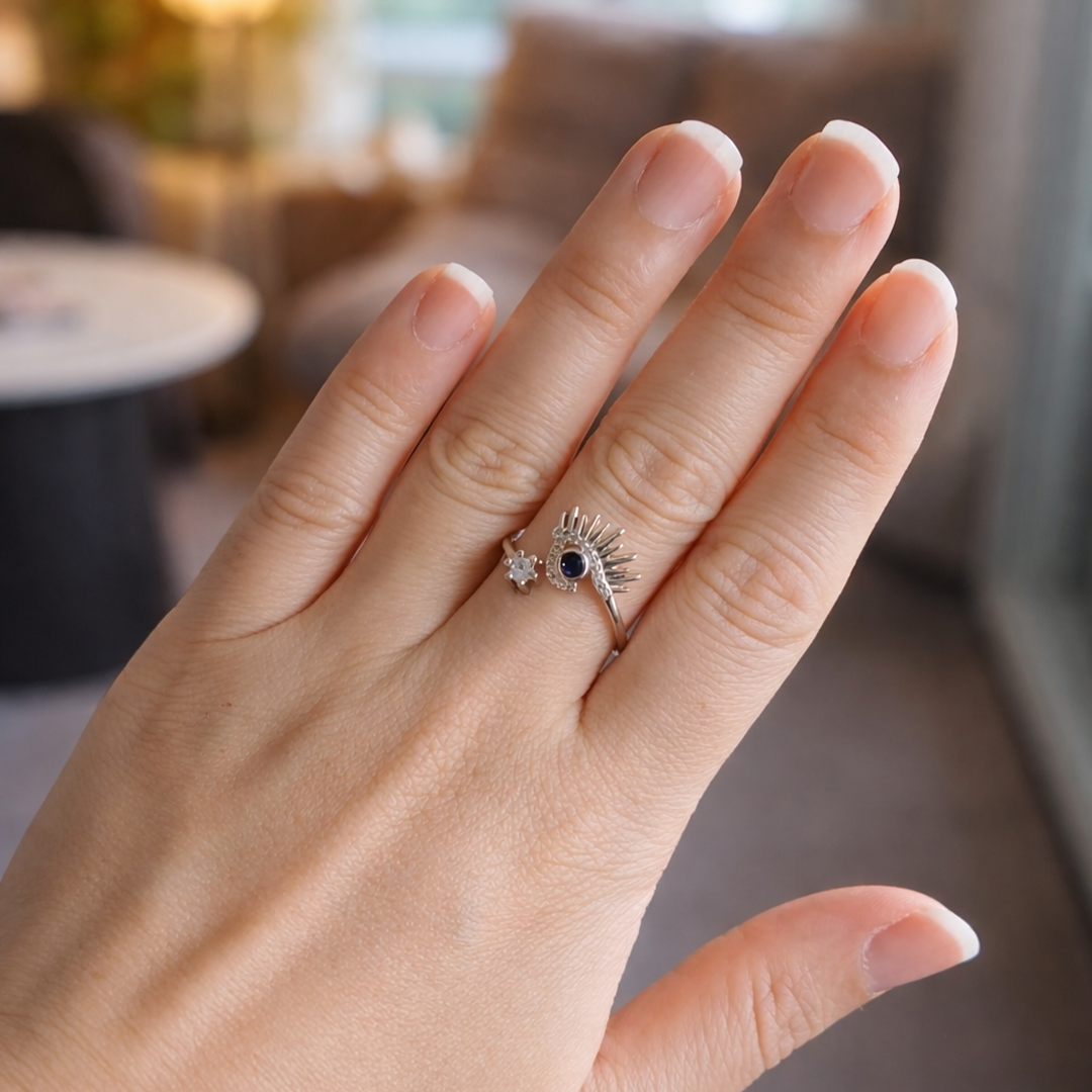 Hand wearing a sterling silver ring with a blue gemstone
