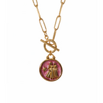Gold plated necklace with a pink pendant featuring a design of two women figures and a star 