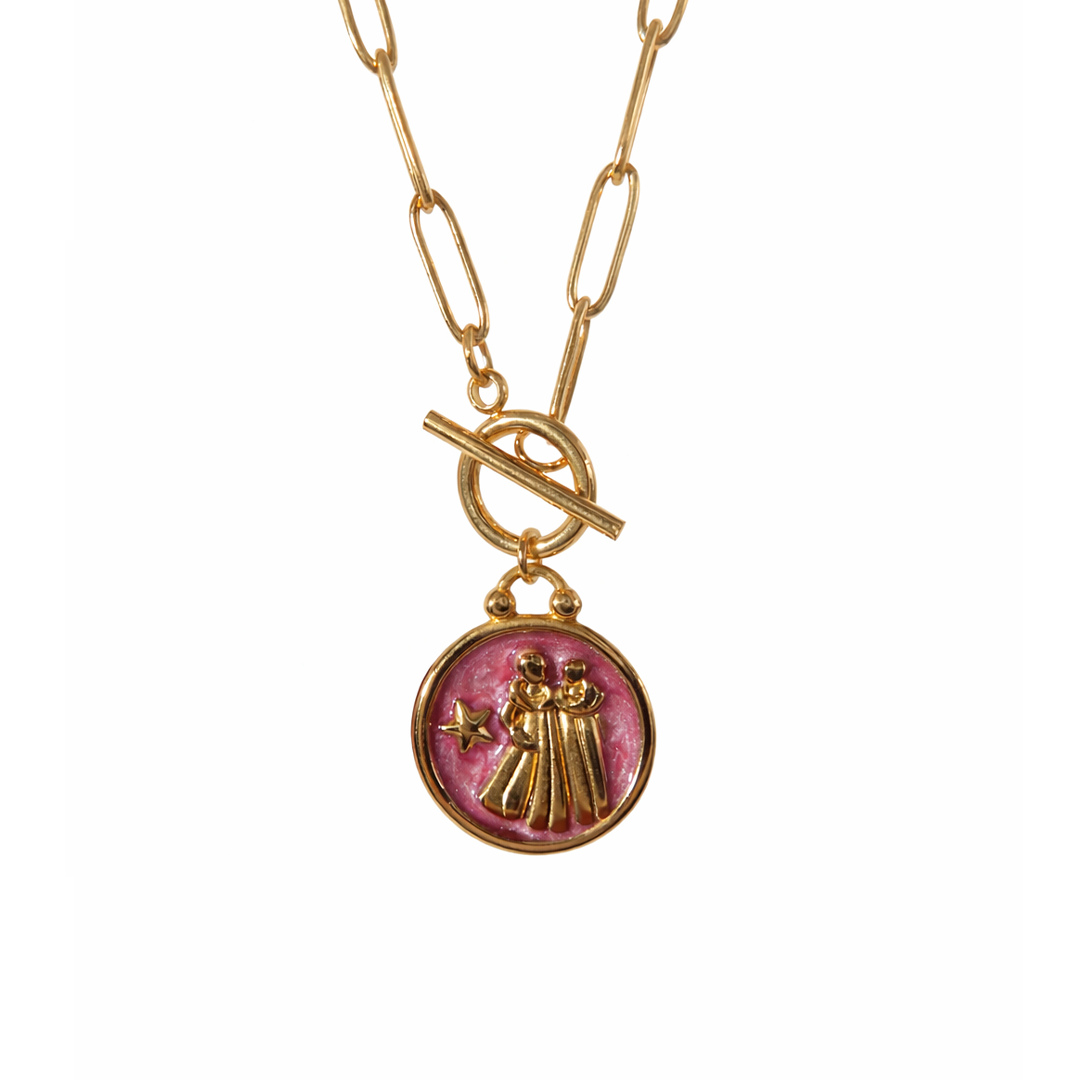 Gold plated necklace with a pink pendant featuring a design of two women figures and a star 