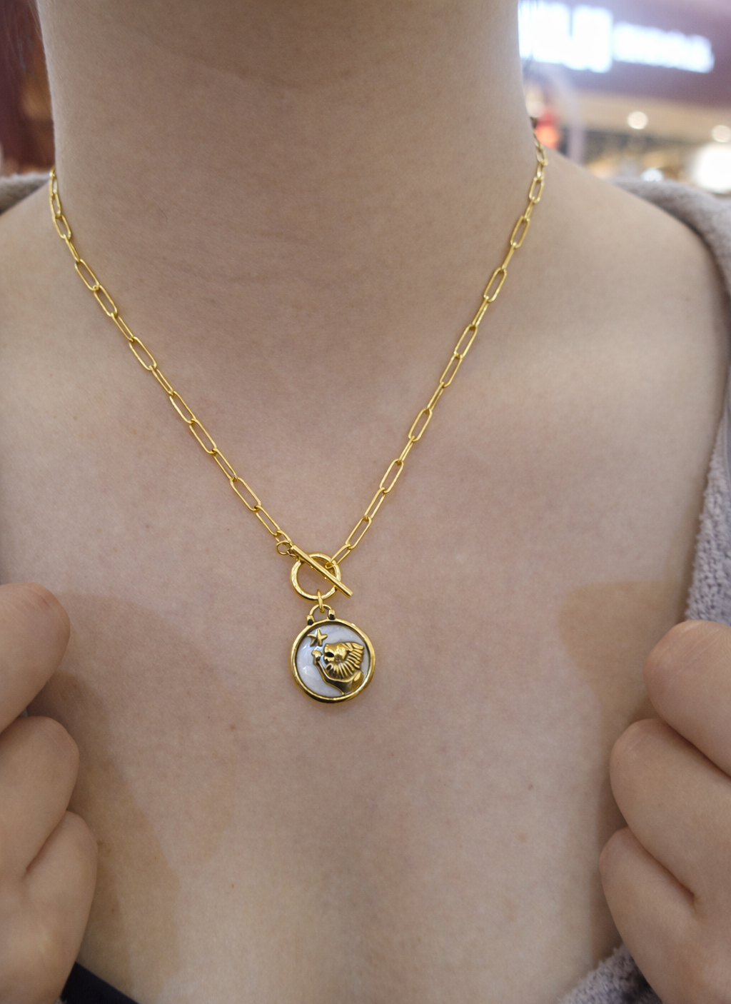 Leo necklace  Gold necklace with a pendant on a person's neck