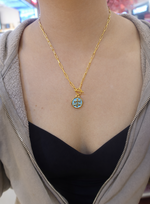 Gold plated necklace with a blue libra pendant worn by a person 