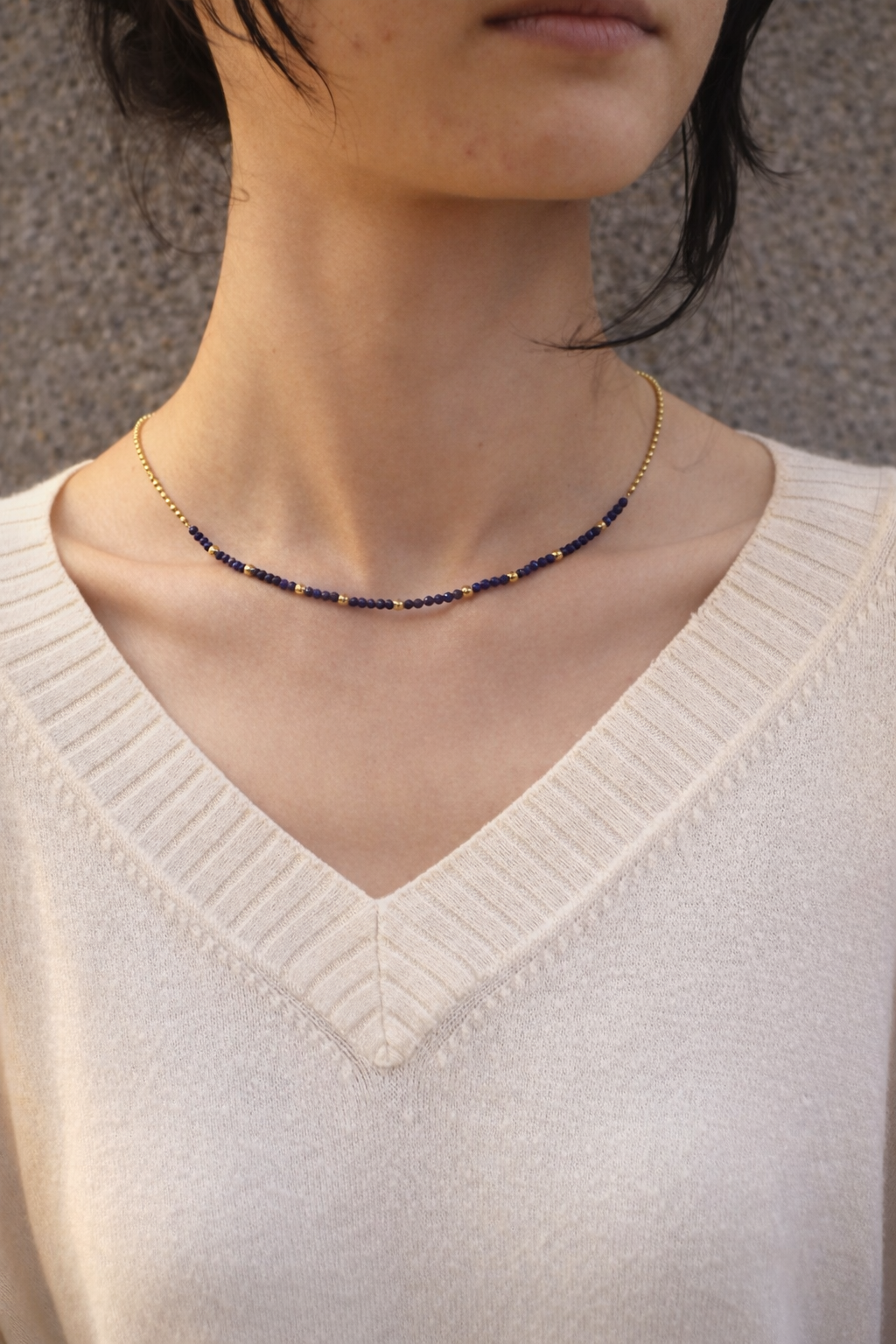 Linked joy necklace with dark blue beads worn by a person 