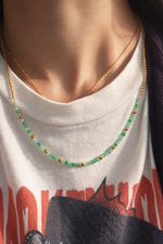 Linked joy necklace with green and gold beads worn