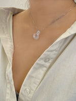 sterling silver necklace with a pendant that has a snake shape on top with green eyes