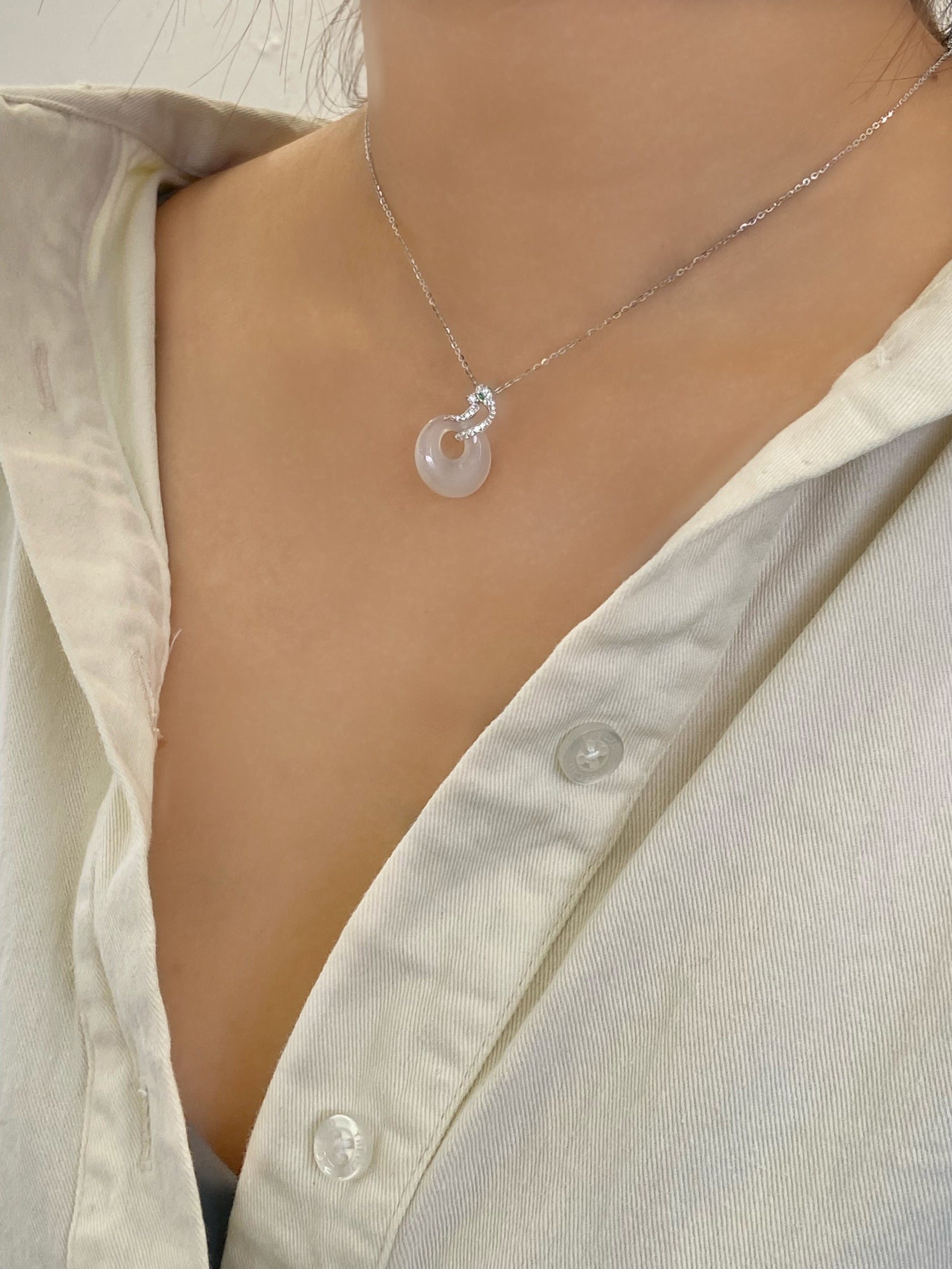 sterling silver necklace with a pendant that has a snake shape on top with green eyes