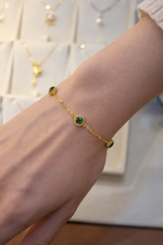 Queen bracelet on women’s wrist with green gemstones 