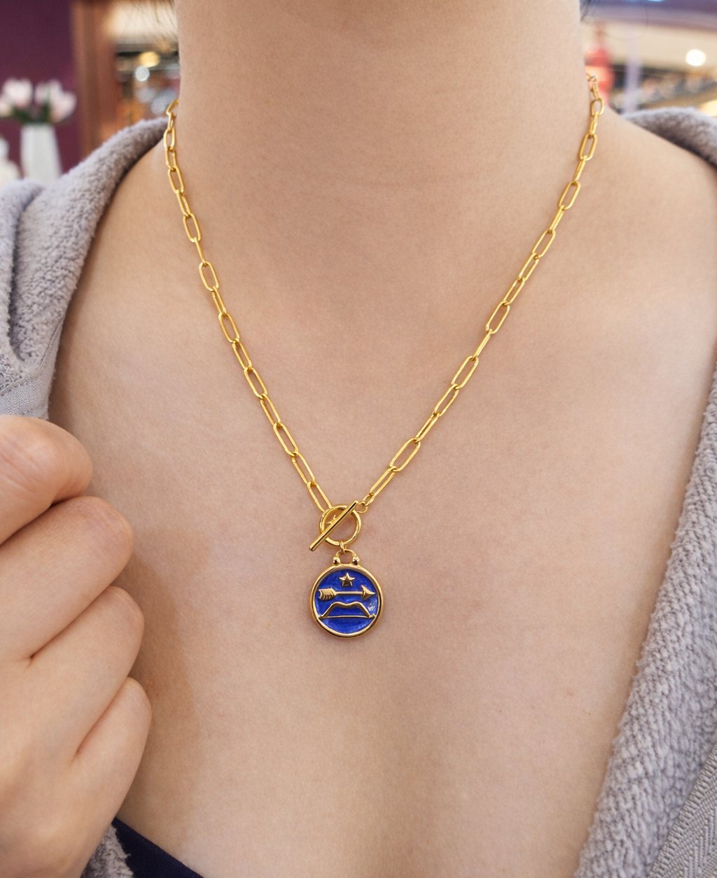 Sagittarius necklace women wearing gold plated stainless necklace with a blue pendant featuring a star and arrow design in resin