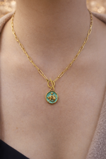 Gold necklace with a green pendant on a person's neck